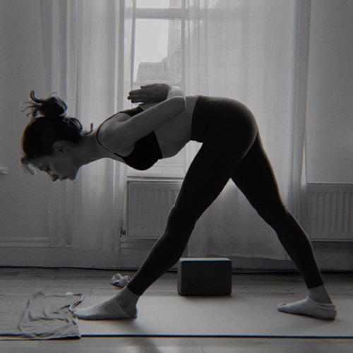 A woman in pyramid pose with hands in reverse prayer position in the back